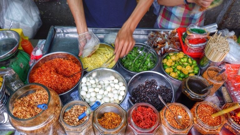 Street food vendor preparing Vietnamese snack bánh tráng trộn (mixed rice paper). | Source: Foody