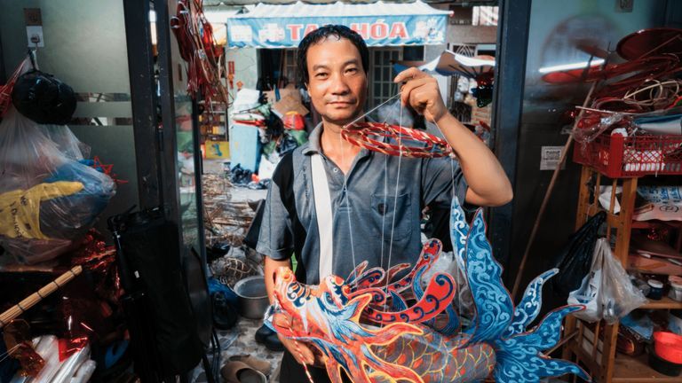 Anh Nguyễn Trọng Bình, nghệ nhân đời thứ ba của Phú Bình cùng chiếc đèn lồng con cá, một trong những tác phẩm mới của anh. | Ảnh bởi Danky cho Vietcetera.