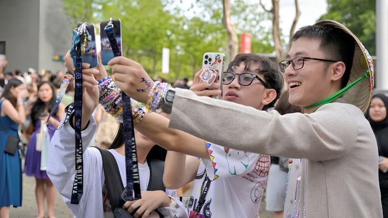Vietnamese fans taking picture of their concert passes at the National Stadium during Taylor Swift’s Eras Tour concert in Singapore | Source: Reuters.